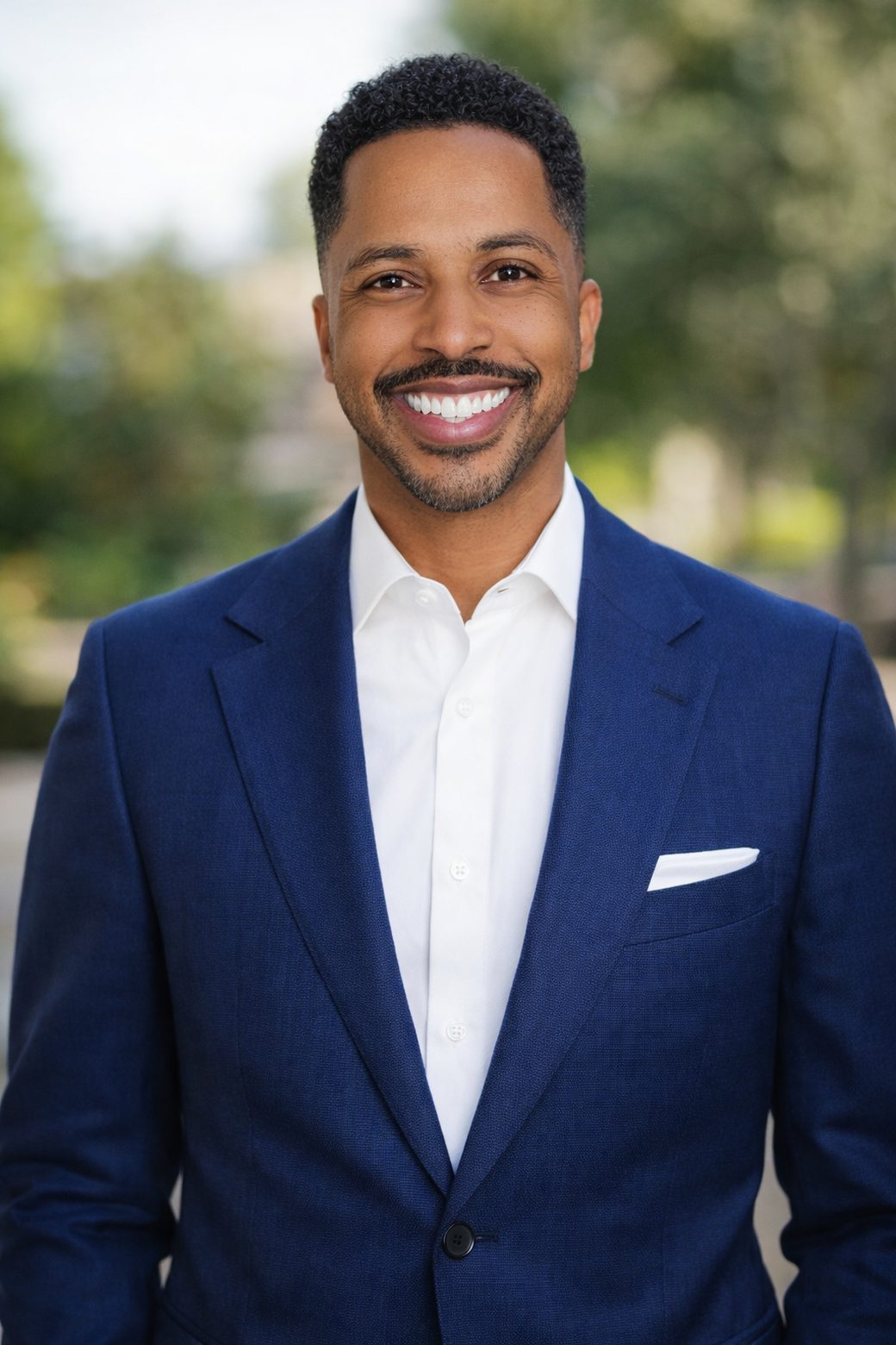 Richard Baltimore, smiling, in a navy suit and white shirt outdoors